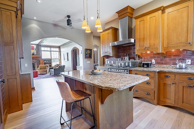 kitchen with ceiling fan, backsplash, light hardwood / wood-style flooring, and wall chimney exhaust hood