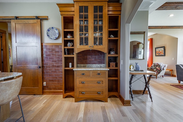 interior space featuring light stone counters, light hardwood / wood-style flooring, and a barn door