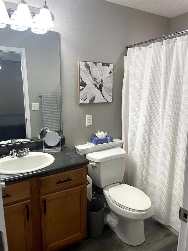 bathroom with a shower with curtain, vanity, hardwood / wood-style flooring, toilet, and a textured ceiling