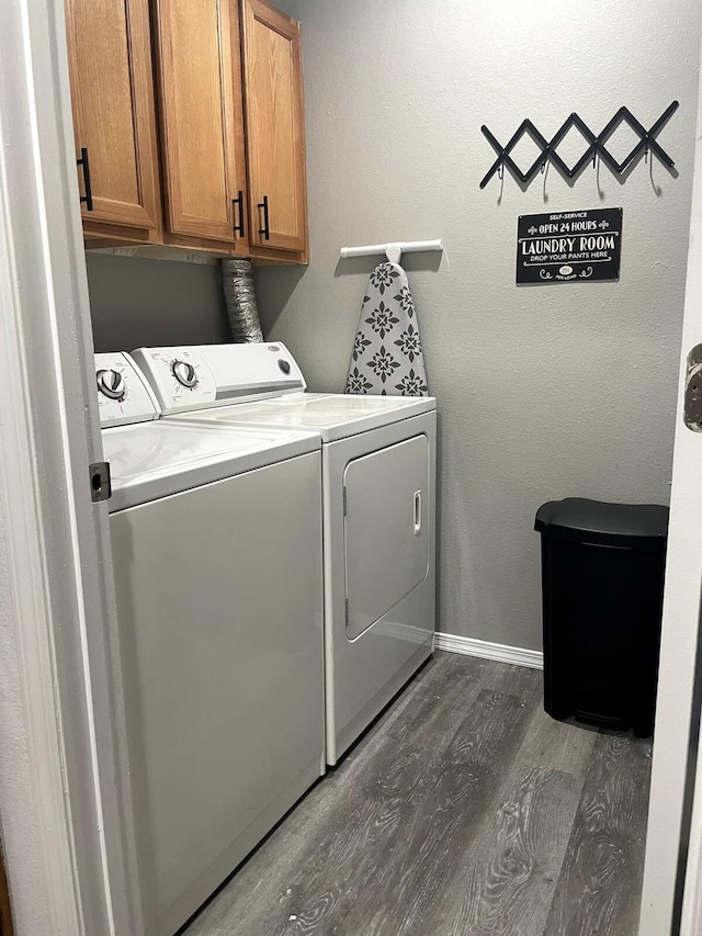 clothes washing area featuring dark hardwood / wood-style floors, washer and dryer, and cabinets