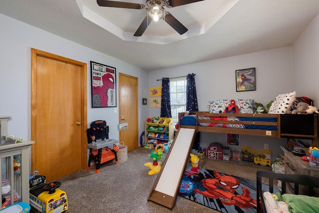 carpeted bedroom with ceiling fan, a raised ceiling, and a textured ceiling