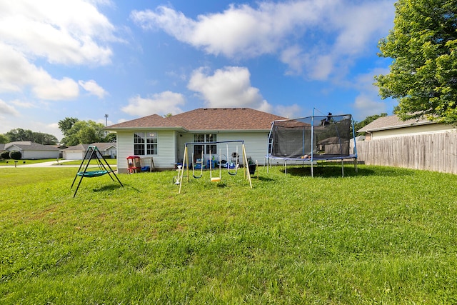 rear view of property with a playground, a yard, and a trampoline