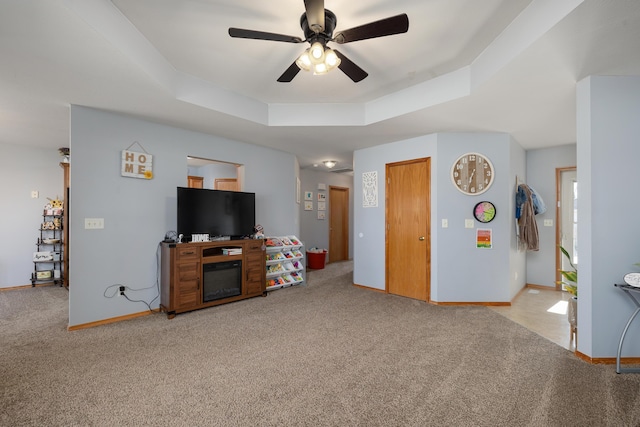 living room featuring ceiling fan, a raised ceiling, and light colored carpet