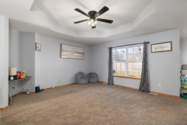 interior space with carpet flooring, ceiling fan, and a tray ceiling