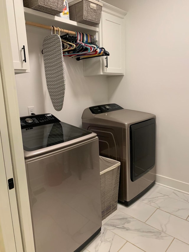 laundry room featuring washer and clothes dryer and cabinets