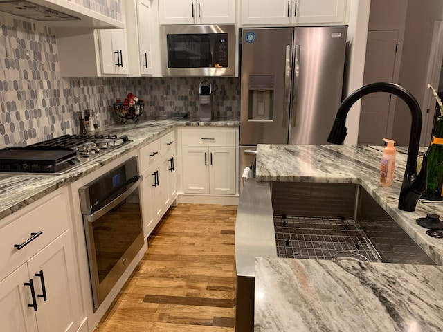 kitchen with light stone countertops, stainless steel appliances, and white cabinetry