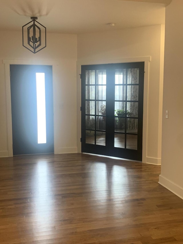 doorway to outside featuring french doors, dark wood-type flooring, and an inviting chandelier