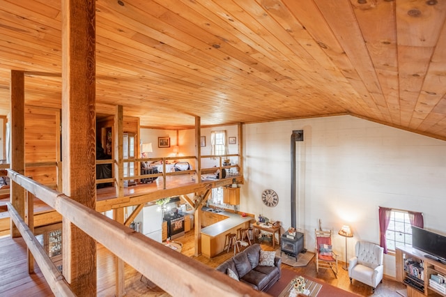 living room with wooden ceiling, vaulted ceiling, hardwood / wood-style floors, and a wood stove