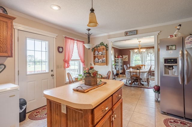 kitchen featuring stainless steel fridge, a wealth of natural light, and decorative light fixtures