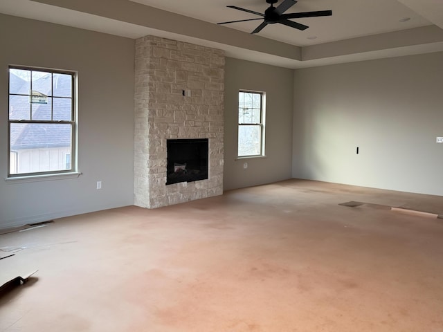 unfurnished living room with a fireplace, carpet, a raised ceiling, and plenty of natural light