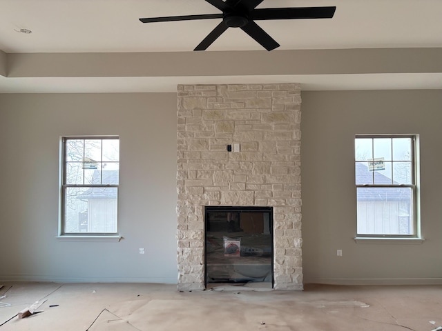 unfurnished living room with a stone fireplace and ceiling fan