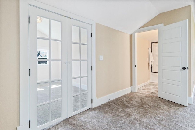 carpeted empty room with lofted ceiling and french doors