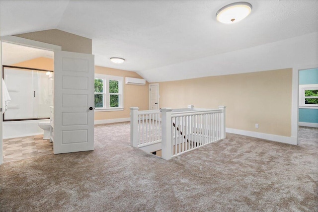 interior space featuring carpet flooring, vaulted ceiling, and a wall unit AC