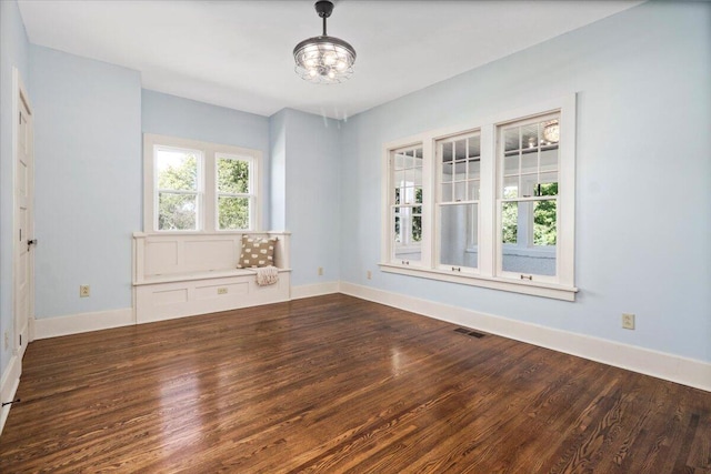 spare room with dark wood-type flooring and an inviting chandelier