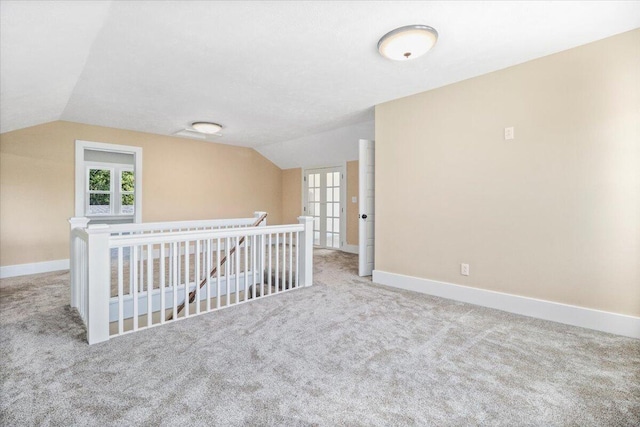 additional living space featuring vaulted ceiling and light carpet