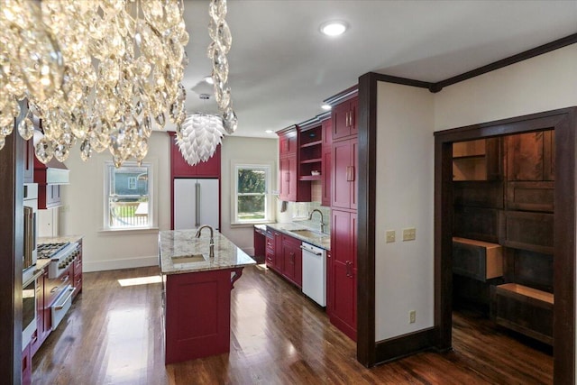 kitchen with light stone counters, pendant lighting, white appliances, a center island with sink, and dark hardwood / wood-style flooring