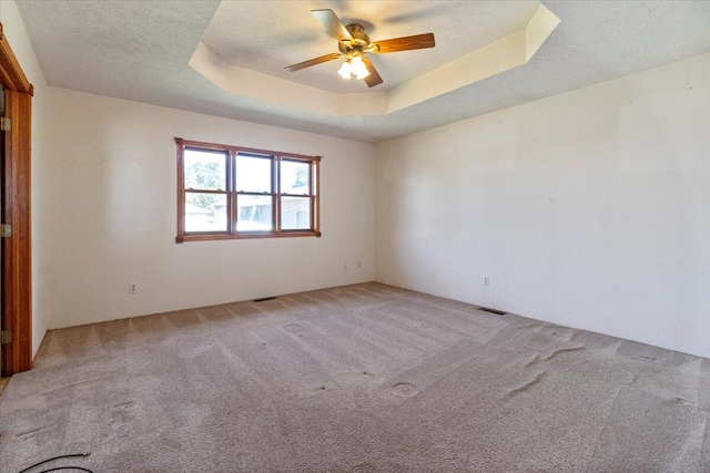 carpeted empty room featuring a raised ceiling, a textured ceiling, and ceiling fan