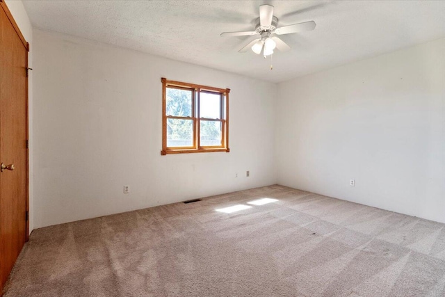 unfurnished room with light carpet, ceiling fan, and a textured ceiling