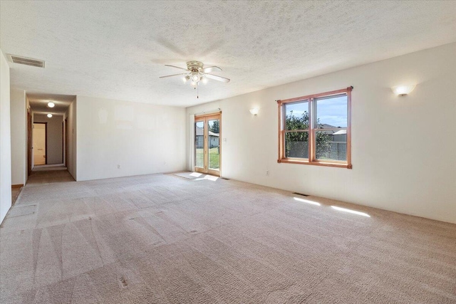 empty room with light colored carpet, a textured ceiling, and ceiling fan