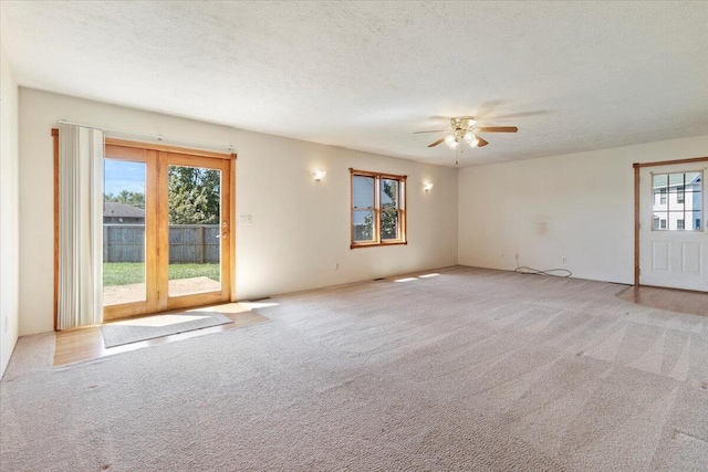 carpeted empty room featuring ceiling fan, a textured ceiling, and plenty of natural light