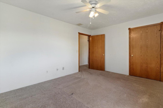 unfurnished bedroom with ceiling fan, a textured ceiling, and carpet