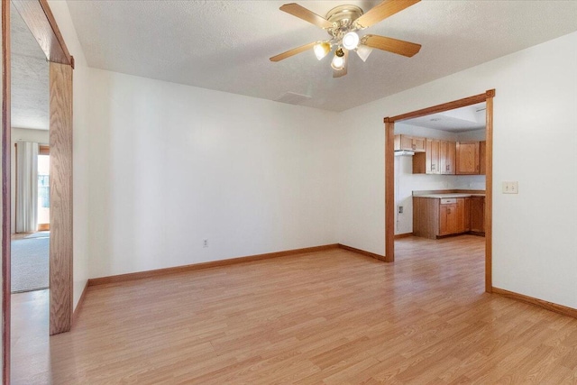 empty room featuring ceiling fan, light hardwood / wood-style floors, and a textured ceiling