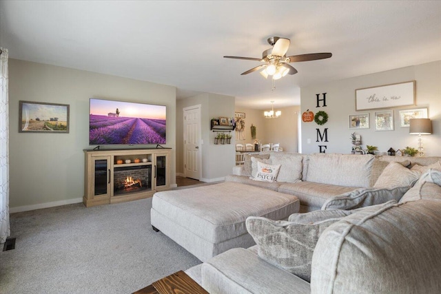 living room with ceiling fan with notable chandelier and carpet