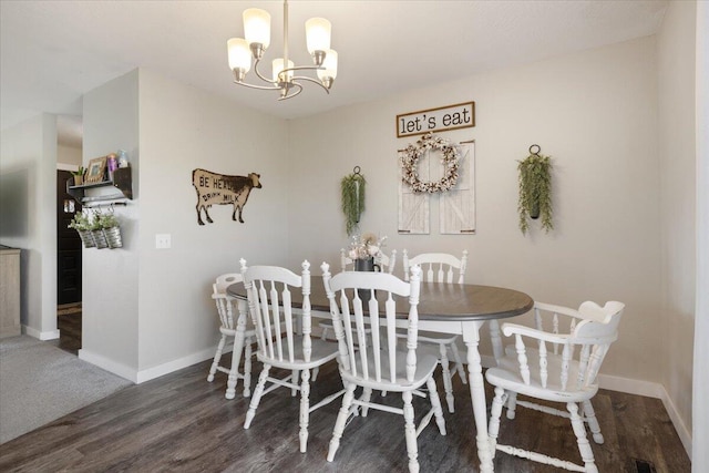 dining space with dark wood-type flooring and a chandelier