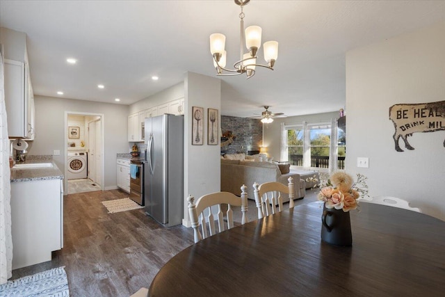 dining area featuring ceiling fan with notable chandelier, dark hardwood / wood-style floors, sink, and washer / dryer