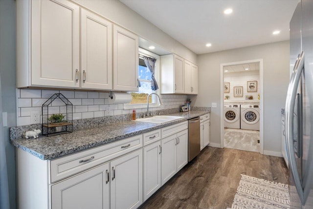 kitchen featuring washing machine and clothes dryer, dark hardwood / wood-style flooring, sink, appliances with stainless steel finishes, and white cabinetry