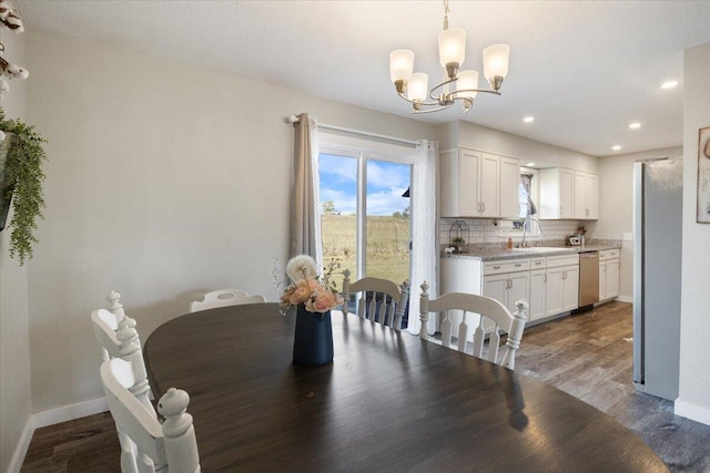 dining room with sink, a chandelier, and dark wood-type flooring