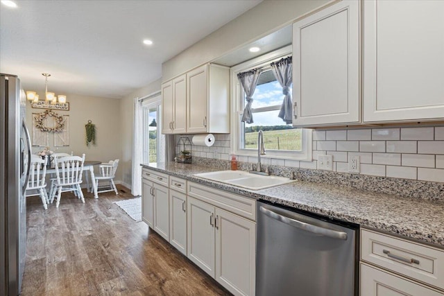 kitchen featuring white cabinets, sink, dark wood-type flooring, stainless steel appliances, and decorative backsplash