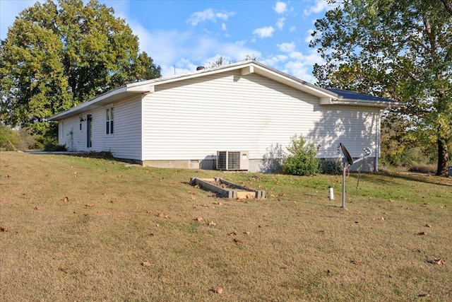 view of side of home with a yard and central AC