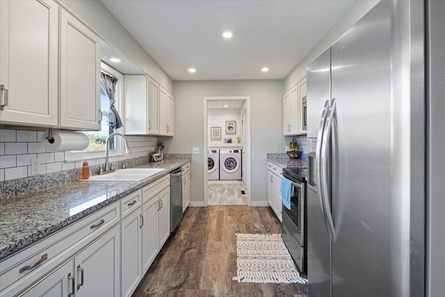 kitchen with washing machine and clothes dryer, white cabinetry, sink, and stainless steel appliances