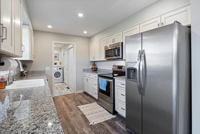 kitchen featuring dark wood-type flooring, sink, washer / dryer, appliances with stainless steel finishes, and white cabinetry