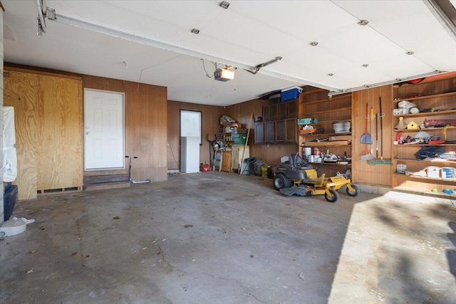 garage featuring a garage door opener and wooden walls