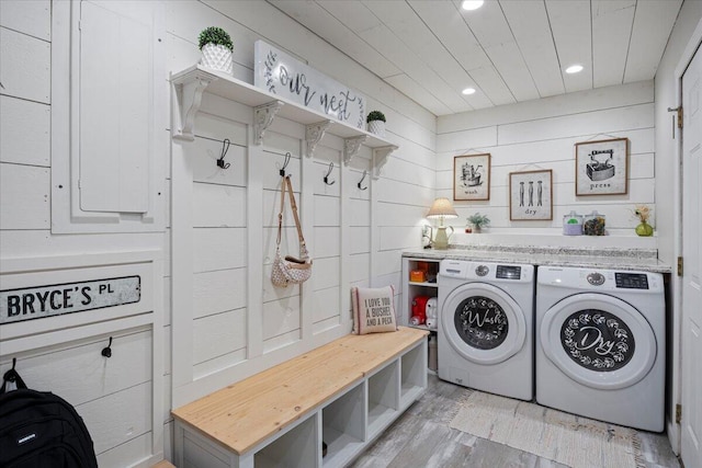 laundry room featuring washer and dryer, wood walls, and light hardwood / wood-style floors