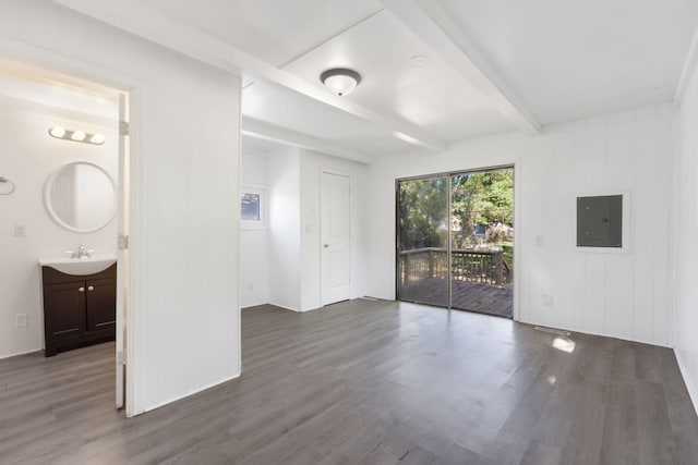 unfurnished room with electric panel, beamed ceiling, dark hardwood / wood-style flooring, and sink