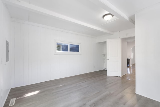 unfurnished room with wood walls, hardwood / wood-style floors, and beam ceiling