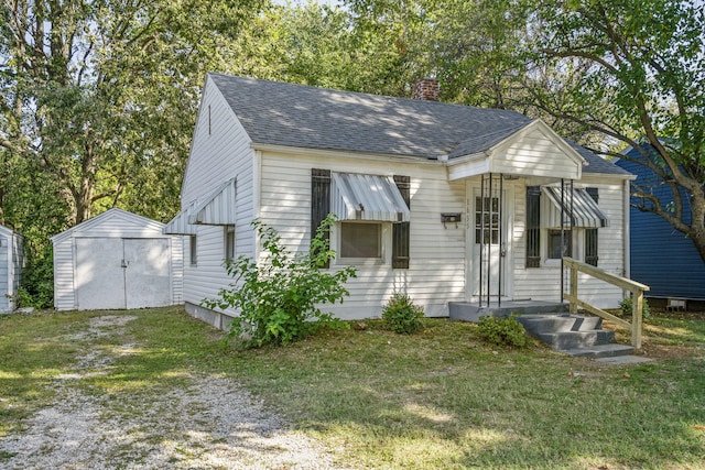 bungalow-style house with a front lawn and a storage unit