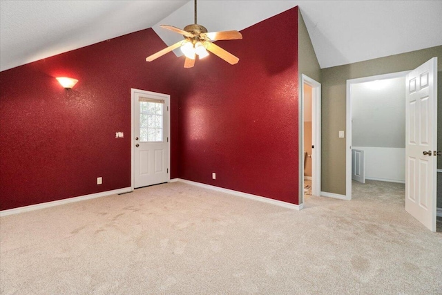 carpeted spare room with ceiling fan and vaulted ceiling