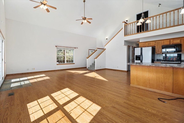 unfurnished living room with high vaulted ceiling, ceiling fan, and light hardwood / wood-style floors