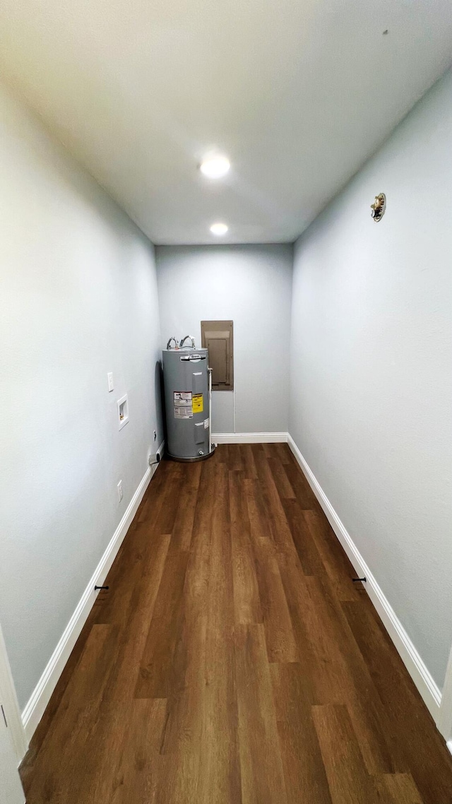 below grade area with baseboards, dark wood-style floors, and electric water heater