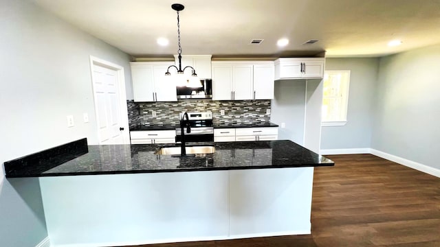 kitchen featuring stainless steel appliances, backsplash, visible vents, dark stone counters, and baseboards
