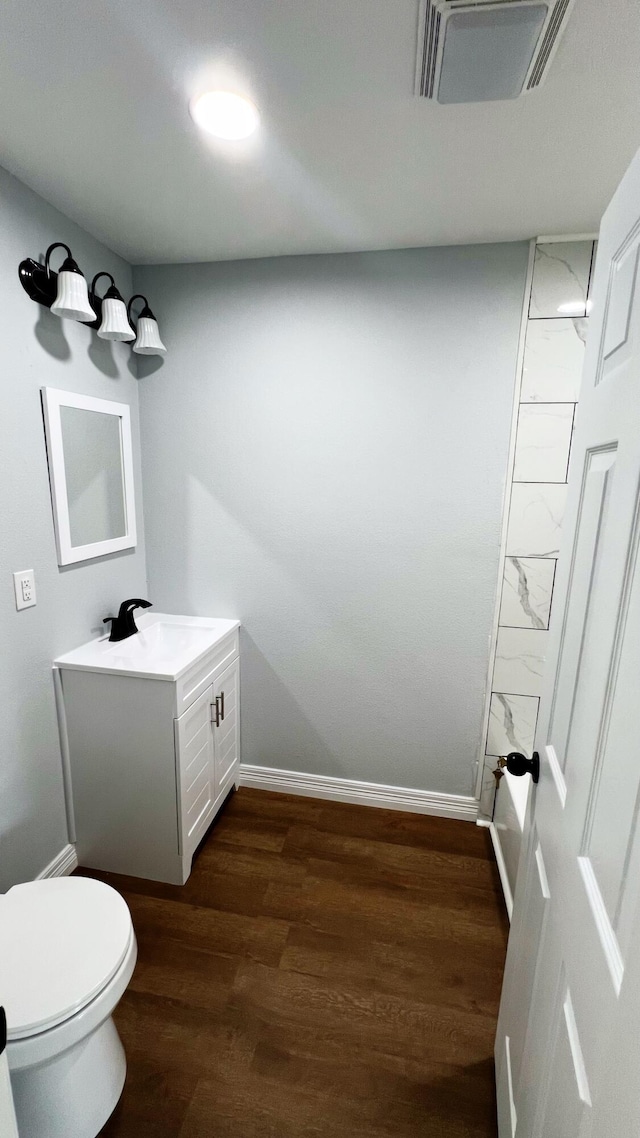 bathroom featuring toilet, baseboards, visible vents, wood finished floors, and vanity