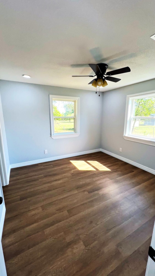spare room featuring ceiling fan, baseboards, and dark wood-style flooring