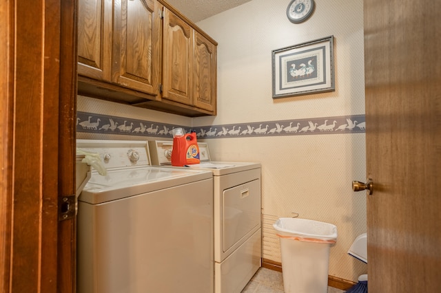 washroom with washing machine and dryer, a textured ceiling, light tile patterned flooring, and cabinets