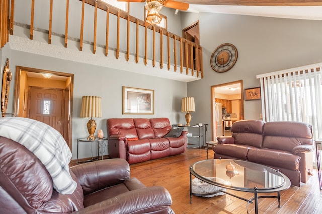 living room with high vaulted ceiling and light hardwood / wood-style flooring