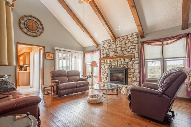 living room featuring high vaulted ceiling, a fireplace, beam ceiling, and hardwood / wood-style floors