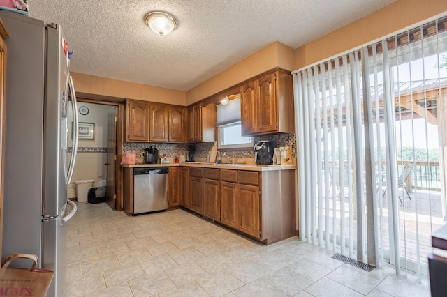 945 Ozark Rd, Nixa, MO 65714 - kitchen featuring brown cabinets, stainless steel appliances, light countertops, visible vents, and decorative backsplash